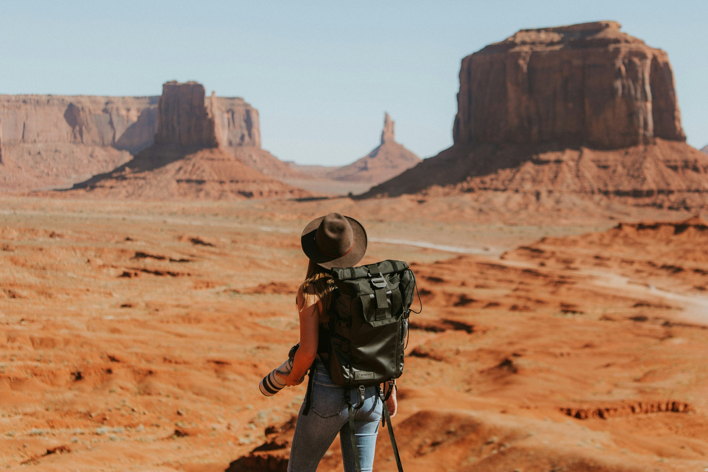 Voyageuse avec appareil photo face aux formations rocheuses de Monument Valley, voyage sur mesure Onvoyage
